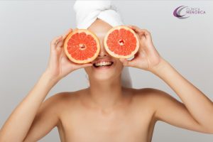 Mujer tapándose los ojos con dos pomelos. Vitaminas faciales.